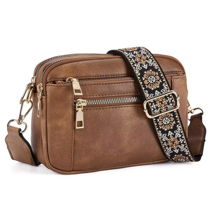 Brown leather crossbody bag with a decorative strap on a white background