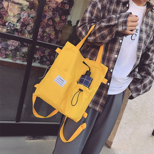 Person wearing a yellow backpack with a small device attached, standing in front of a floral display.