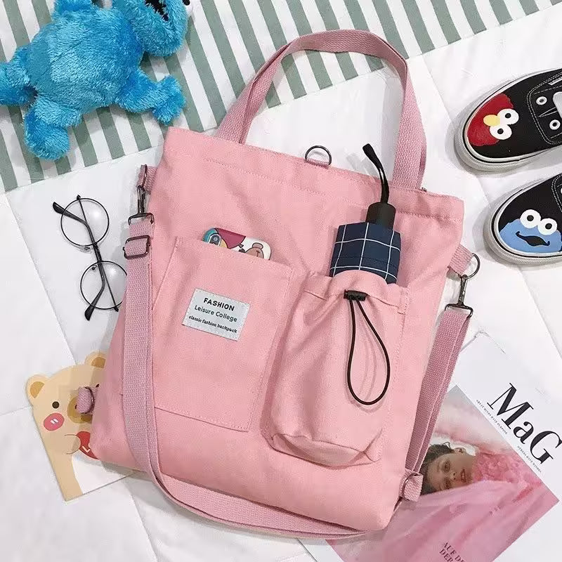 Pink tote bag with various items on a white surface with striped background