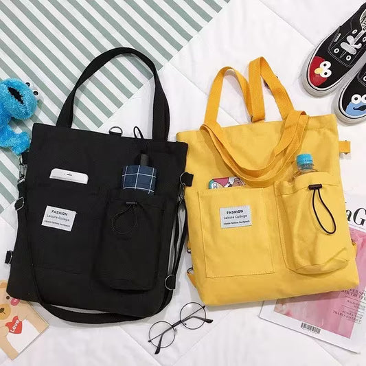 Black and yellow tote bags on a surface with glasses and shoes in the background
