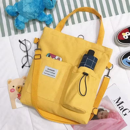 Yellow bag with a strap on a surface with various items including a blue toy and glasses.