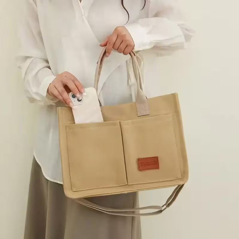 Beige tote bag held by a person against a plain background