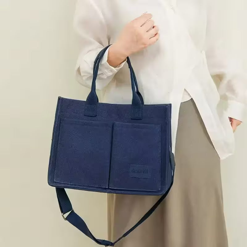 Person holding a navy blue tote bag against a plain background