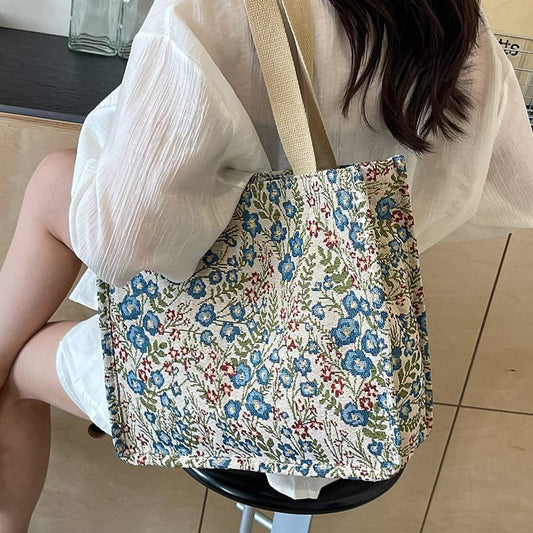 Person holding a floral tote bag on a tiled floor
