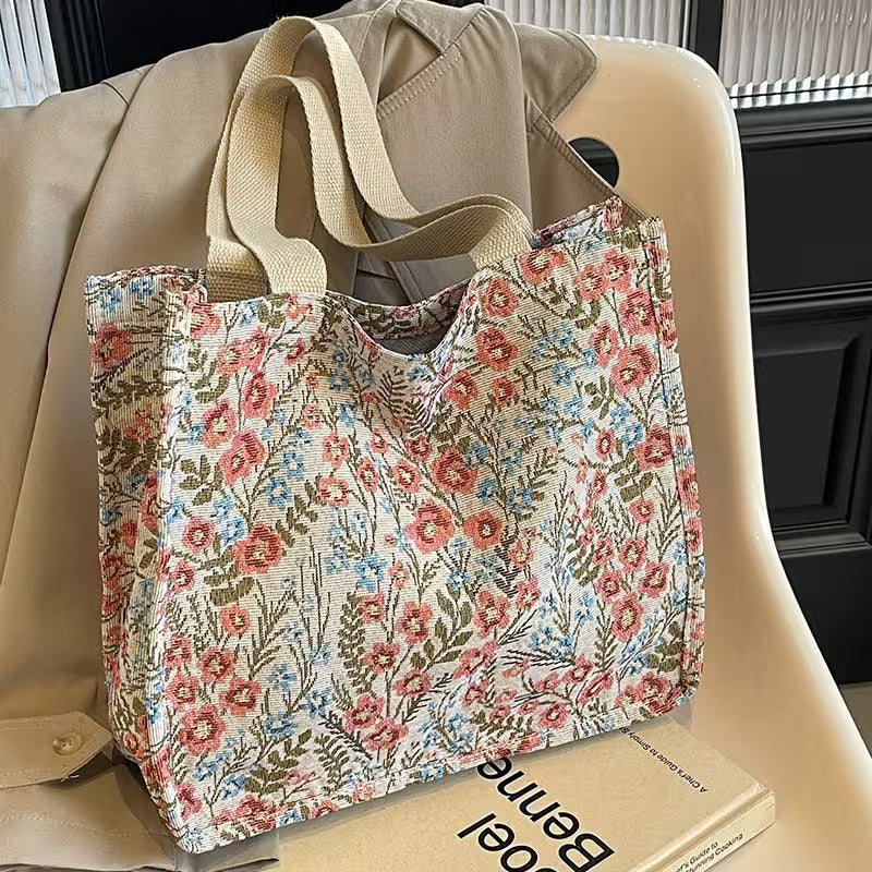 Floral-patterned tote bag on a beige chair with a book underneath
