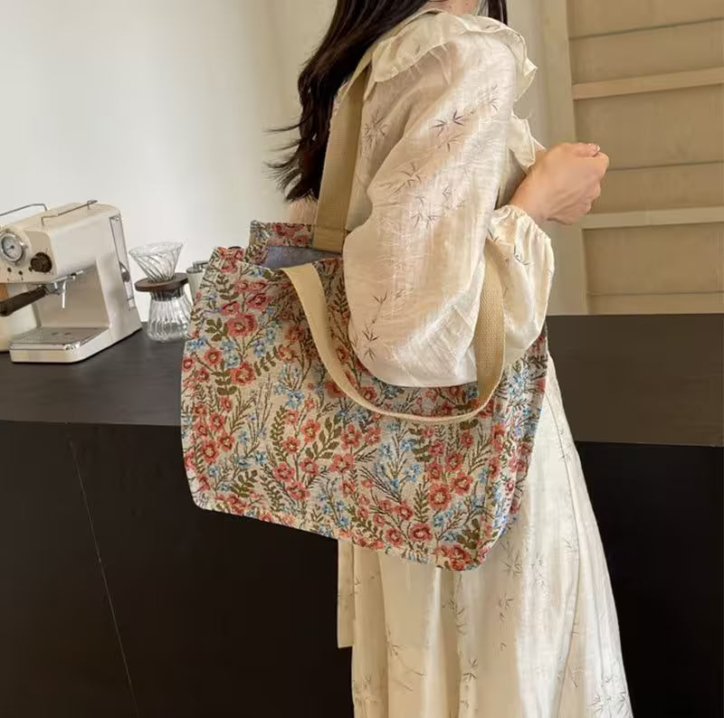 Person holding a floral-patterned bag in a room with a sewing machine.