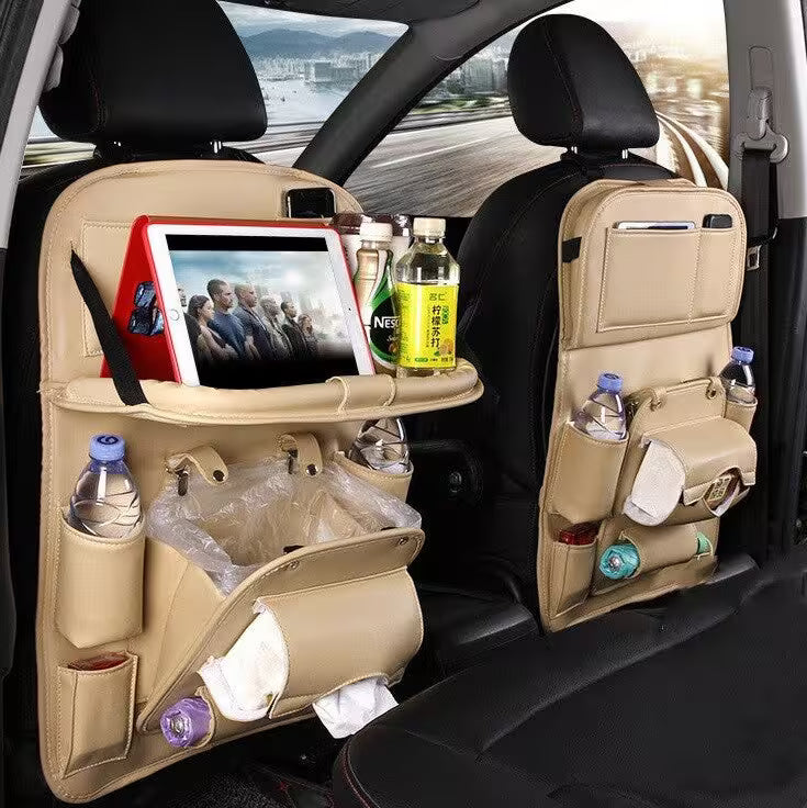 Car seat organizer with multiple pockets and a tablet stand, filled with items, in a car interior.
