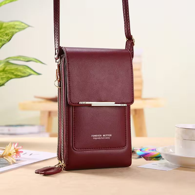 Maroon leather crossbody bag on a light surface with a blurred background