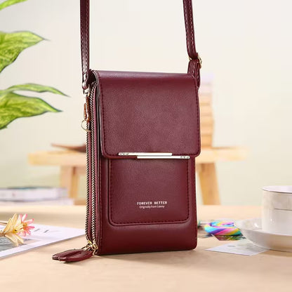 Maroon leather crossbody bag on a light surface with a blurred background