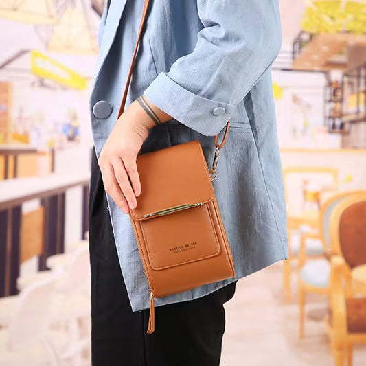 Person holding a brown leather crossbody bag in an outdoor setting