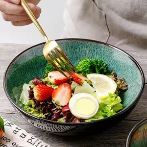 Salad with strawberries and eggs in a decorative bowl on a wooden table.