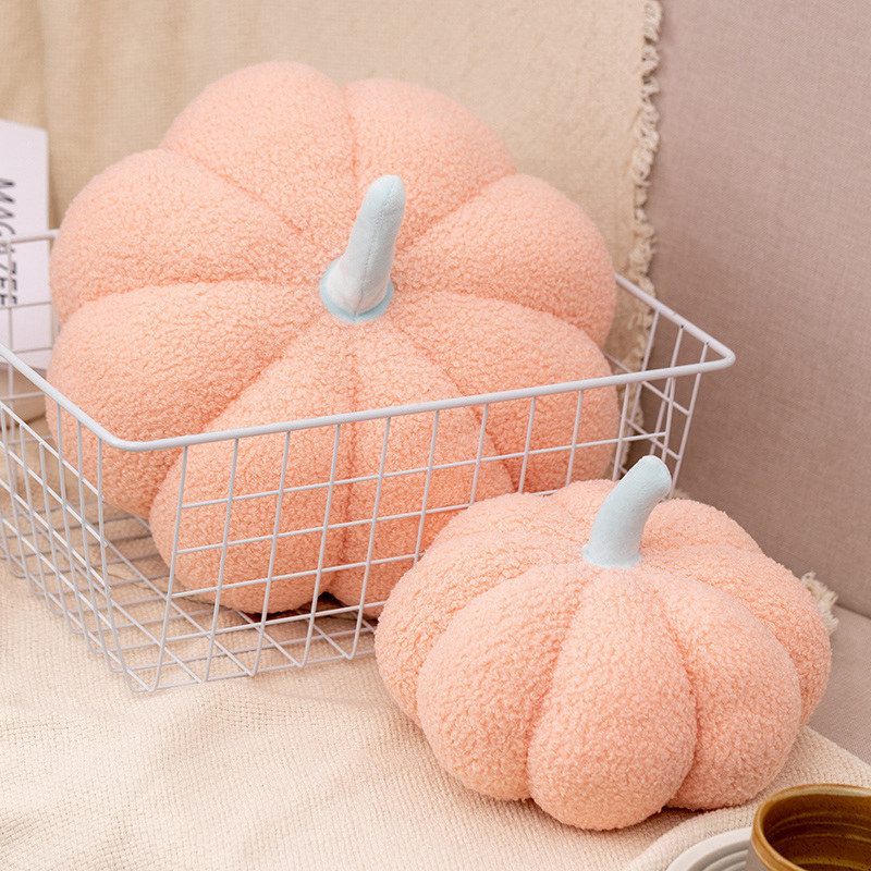 Pink pumpkin-shaped cushions on a white wire basket against a beige background