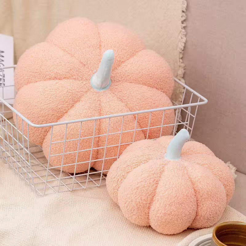 Two pink pumpkin-shaped cushions on a white wire basket with a neutral background