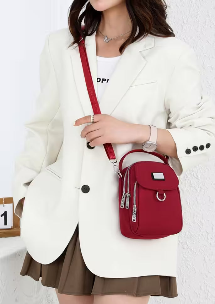 Person wearing a white blazer and holding a red crossbody bag against a white background