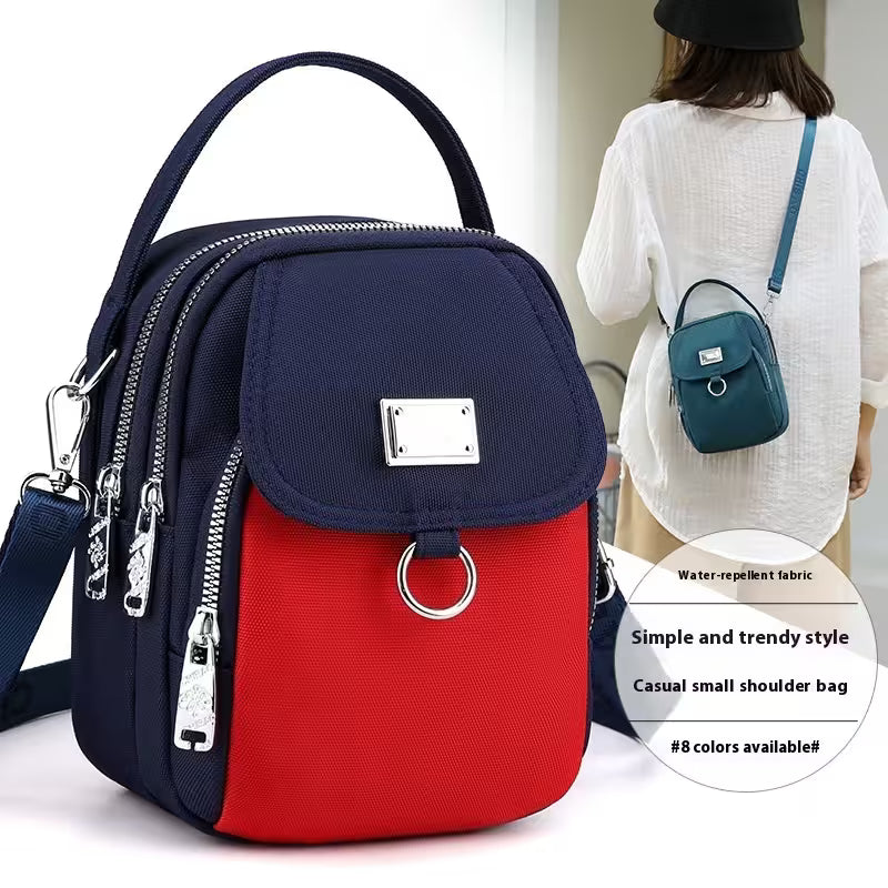 Navy and red backpack with a woman carrying a smaller blue backpack in the background.