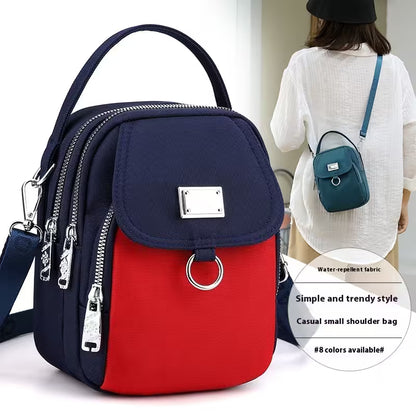 Navy and red backpack with a woman carrying a smaller blue backpack in the background.