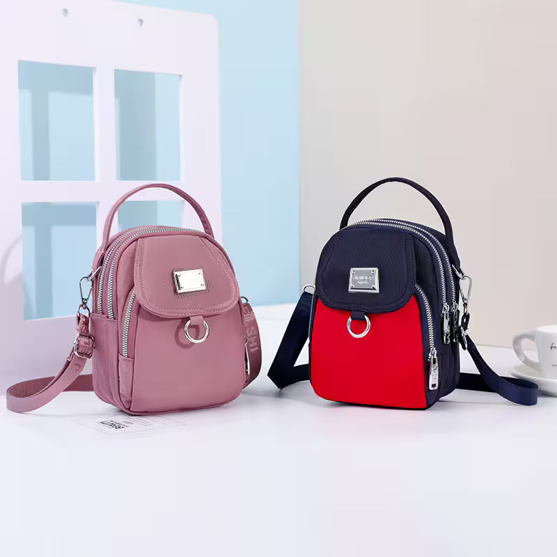 Two backpacks, one pink and one red and black, on a white surface with a light blue wall in the background.
