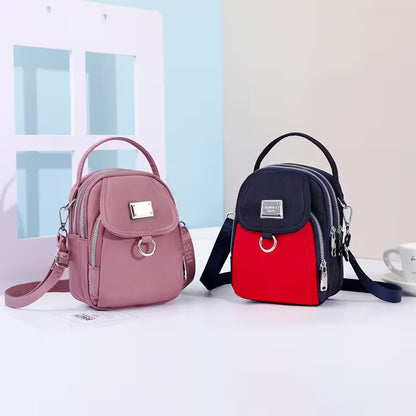 Two backpacks, one pink and one red and black, on a white surface with a light blue wall in the background.