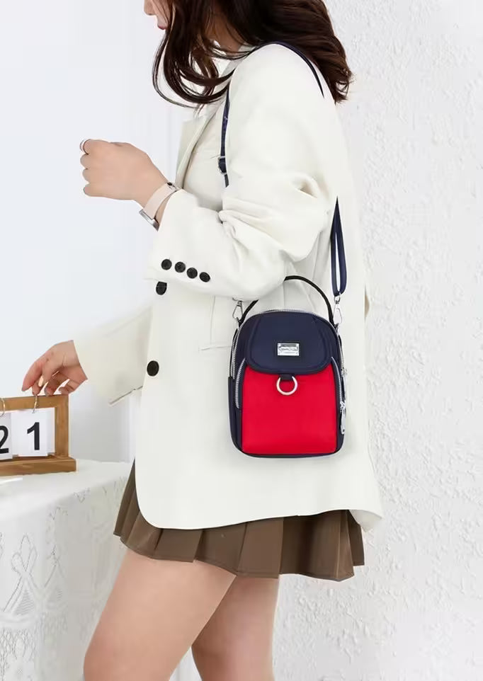 Person wearing a white coat with a red and navy backpack against a white wall.
