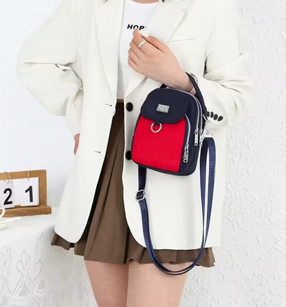 Person holding a red and navy backpack against a white background