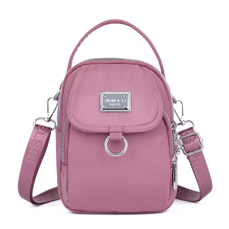 Pink crossbody bag with silver accents on a white background