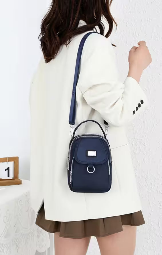 Person wearing a white coat and holding a navy blue backpack against a white background