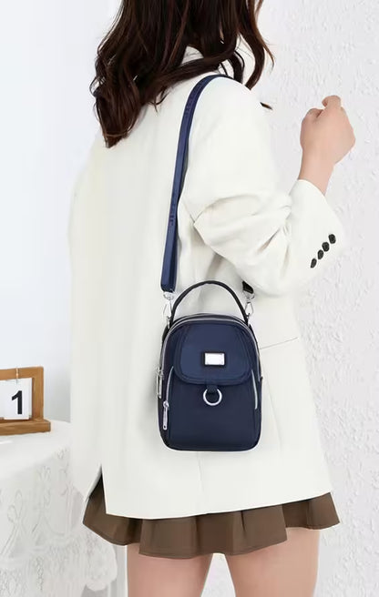 Person wearing a white coat and holding a navy blue backpack against a white background