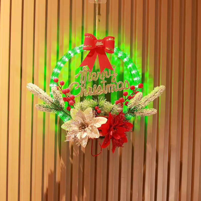 Decorative Christmas wreath with lights, flowers, and a red bow on a wooden background.