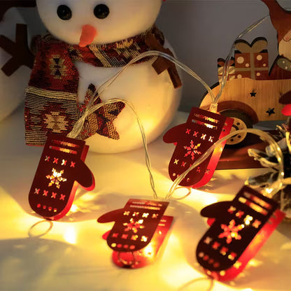 String of red mittens with LED lights in front of a snowman and wooden sled.