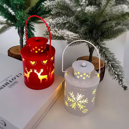 Two decorative lanterns, one red with deer designs and one white with snowflake designs, on a surface with a Christmas tree in the background.