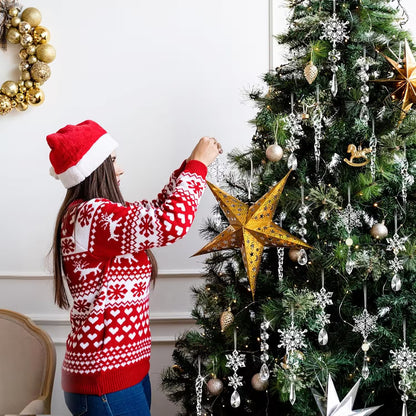 Person decorating a Christmas tree with a gold star ornament, wearing a red and white sweater and Santa hat.