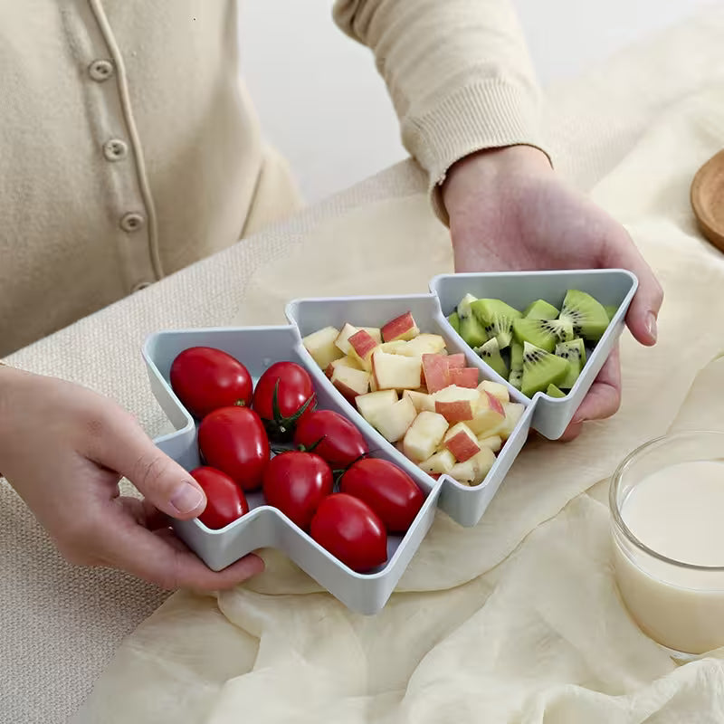 Person holding a triangular fruit and vegetable tray with compartments filled with tomatoes, apples, and kiwis.