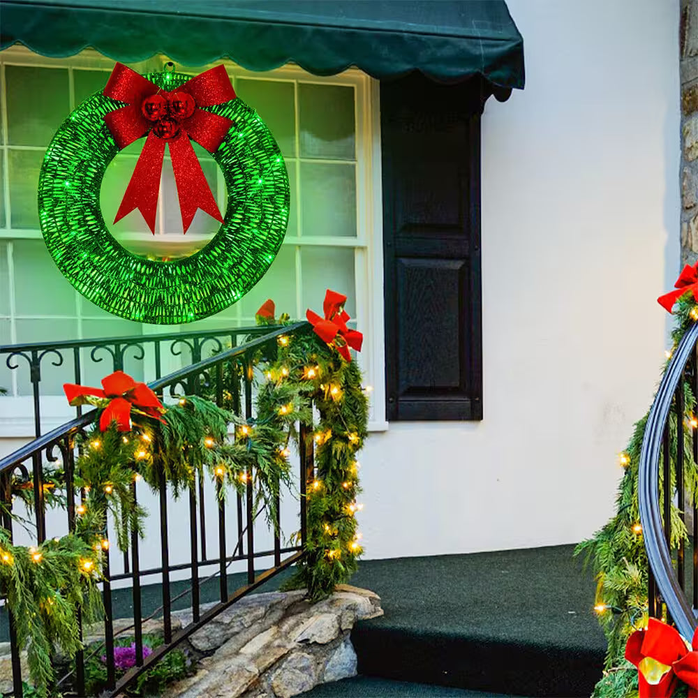 Decorative Christmas wreath with red bow and lights on a staircase railing.
