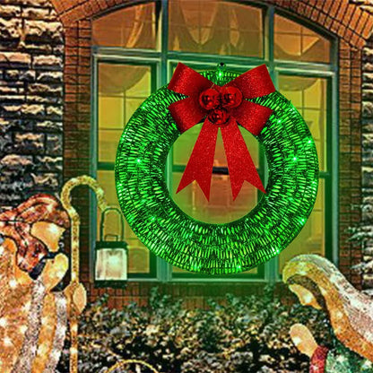 Green Christmas wreath with a red bow in front of a brick building with a window.