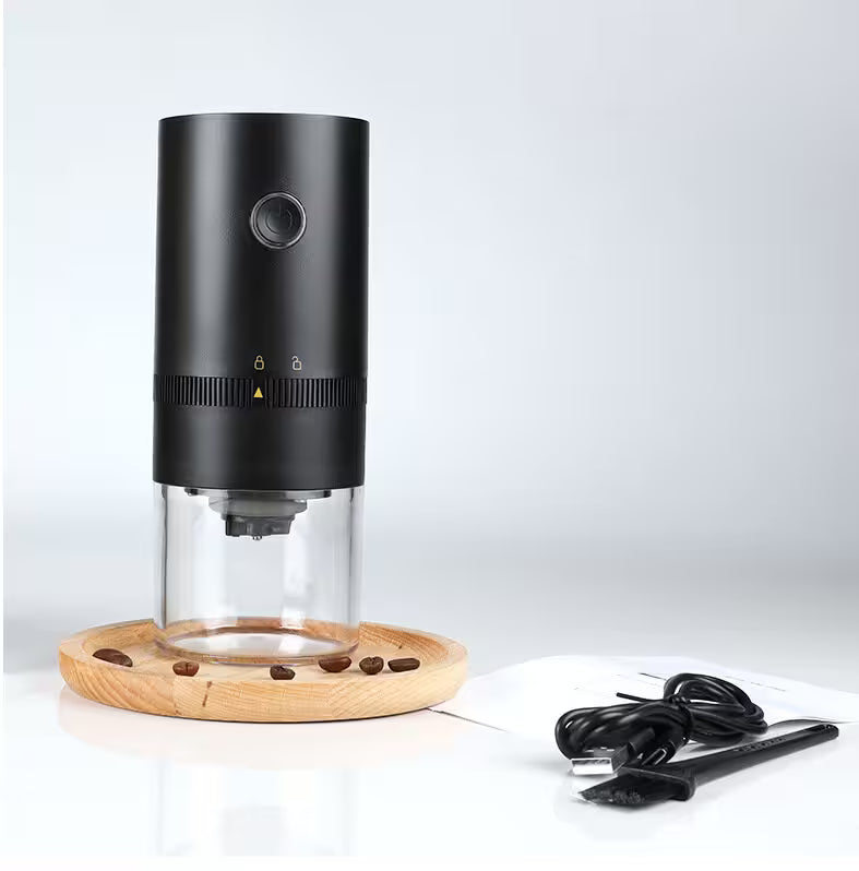 Black coffee grinder with clear container and wooden base on a white background