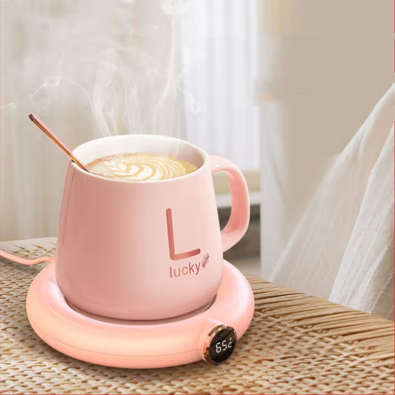 Pink mug with 'lucky' text on a heating pad, filled with a hot beverage.