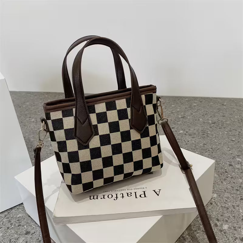 Checkered handbag with brown straps on a white platform