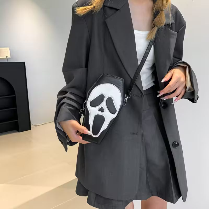 Person wearing a black coat holding a black bag with a white ghost face design.
