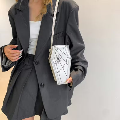 Person wearing a black blazer holding a Halloween-themed coffin bag.