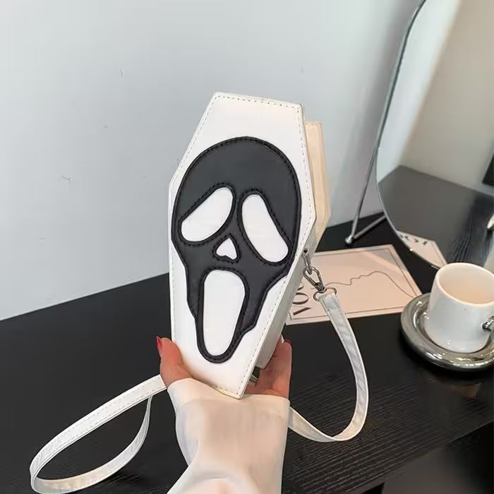 White pouch with black ghost face design held by a hand on a desk.