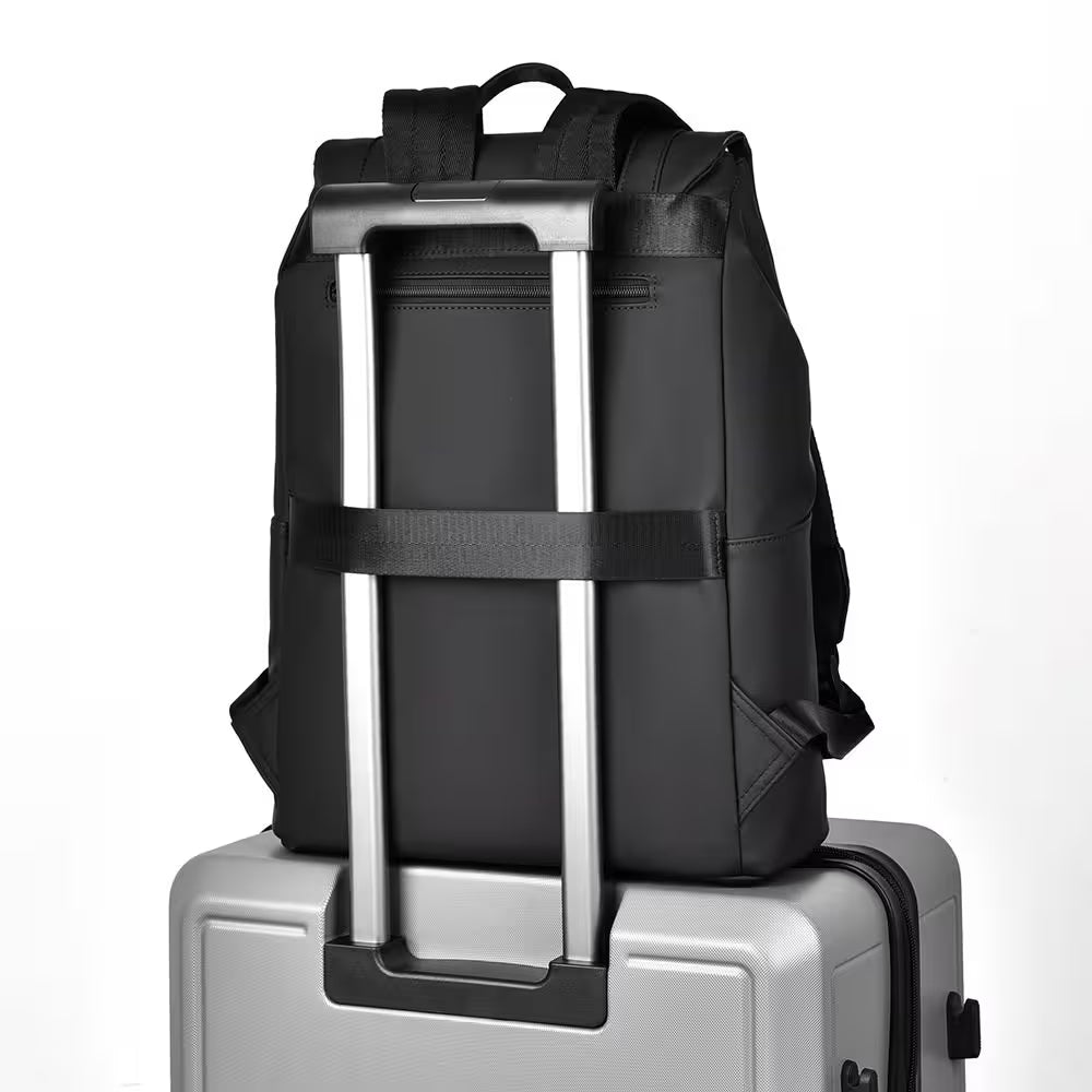 Black backpack on top of a silver suitcase with a white background