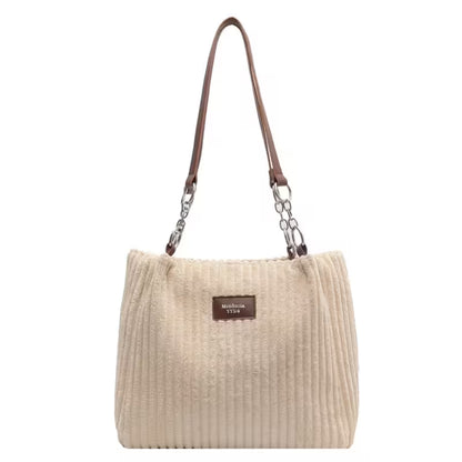 Beige handbag with a brown strap and visible brand label on a white background