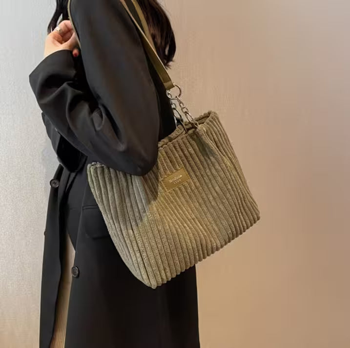 Person holding a beige ribbed handbag with a blurred background
