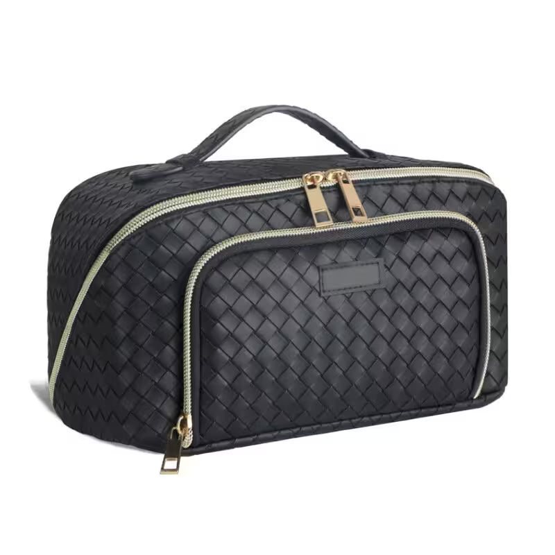 Black woven travel bag with gold zippers on a white background