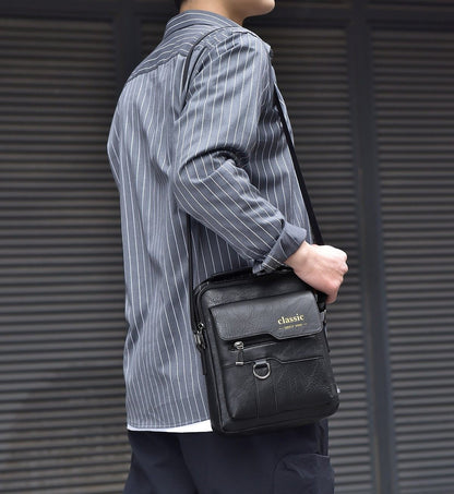 Person holding a black leather bag with 'classic' branding against a metallic background
