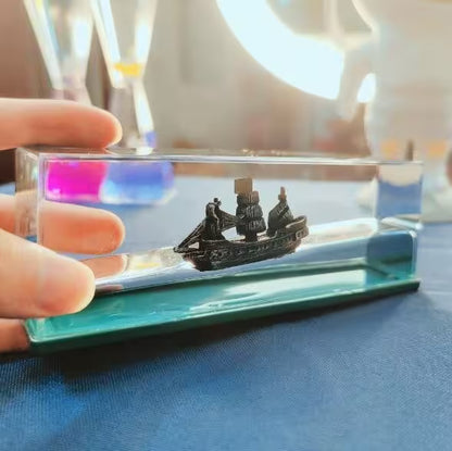 Model ship inside a transparent acrylic display case held by a hand.