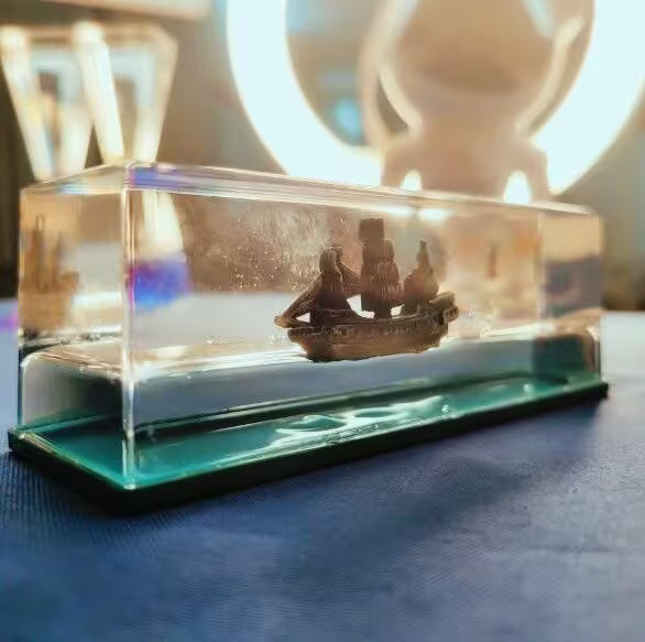 Model ship in a clear display case on a blue surface