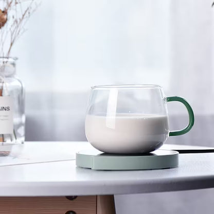 Glass mug with green handle filled with milk on a white surface