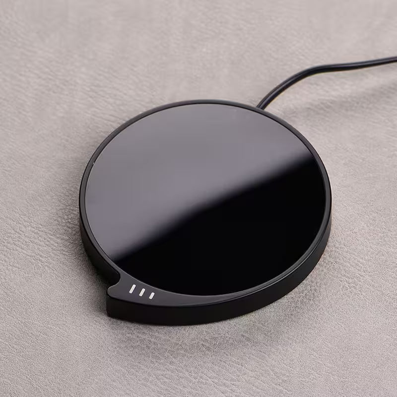 Black wireless charging pad on a gray surface