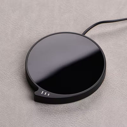 Black wireless charging pad on a gray surface